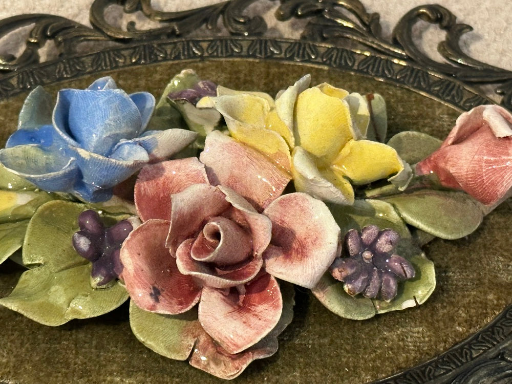Close-up of Capodimonte porcelain flowers, pink rose with blue blossom, yellow rose and purple buds