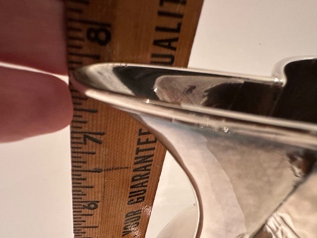 Close-up of the silver pitcher's pouring spout beside a measuring ruler