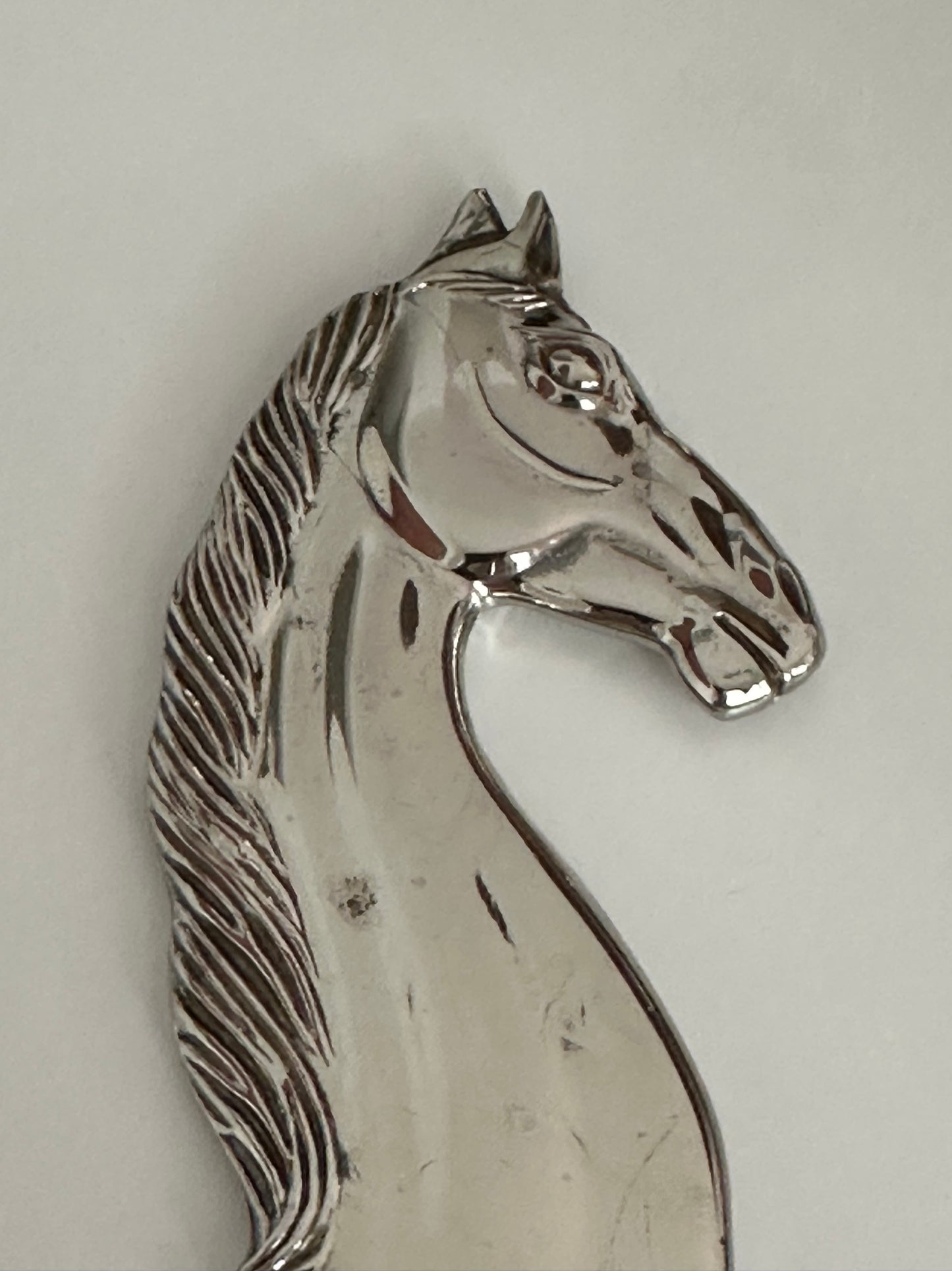 Close-up of the polished horse head on the vintage silver plate bottle opener.