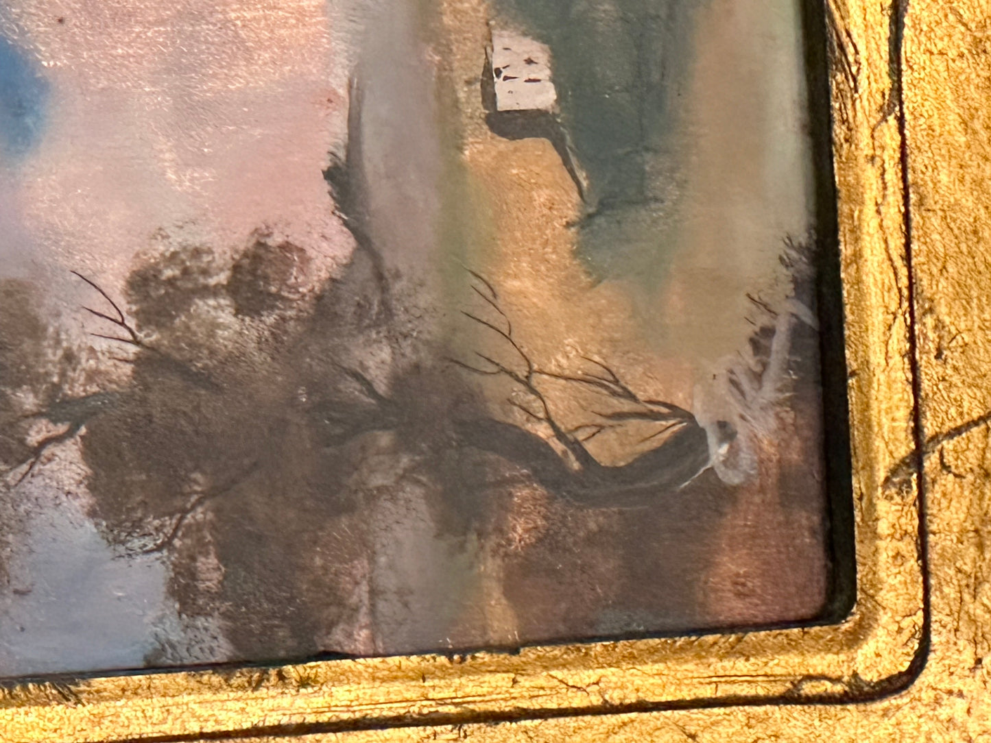 Close-up corner detail of a miniature landscape painting and ornate gilt frame, artist signature visible