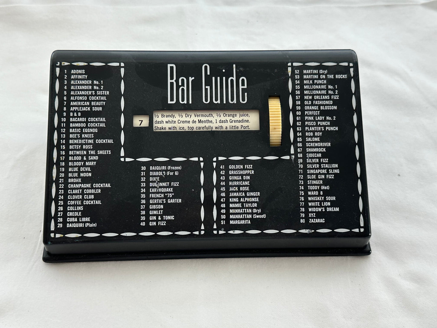 MCM black plastic Bar Guide front view listing 80 numbered cocktails with central recipe window