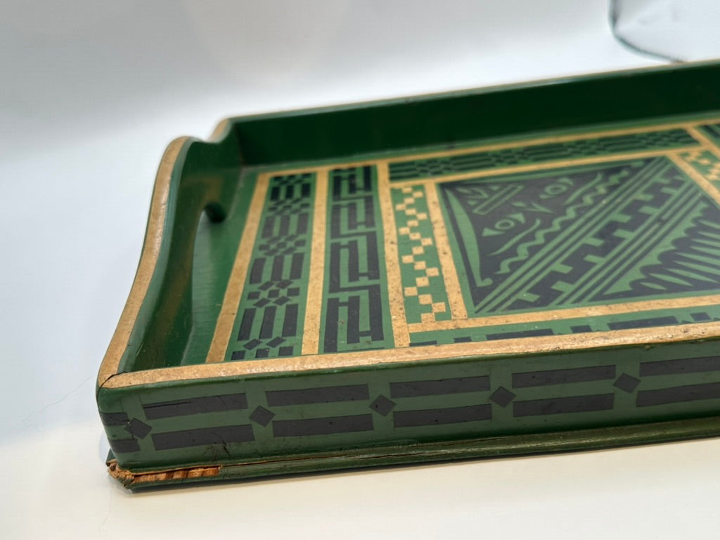 Angled close view of green tray corner showing geometric border and chipped gilt trim
