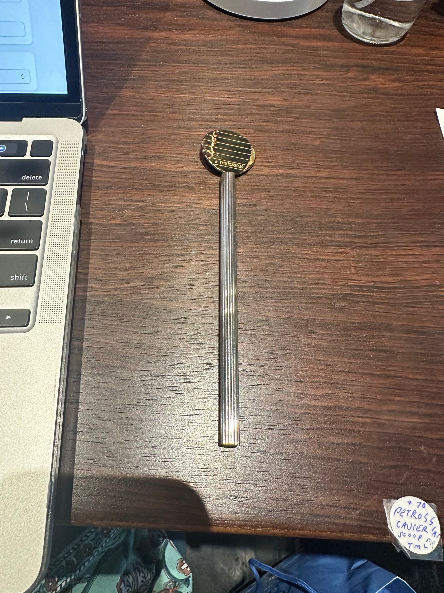 Full Petrossian caviar paddle spoon laid on a table, gilt paddle and long handle