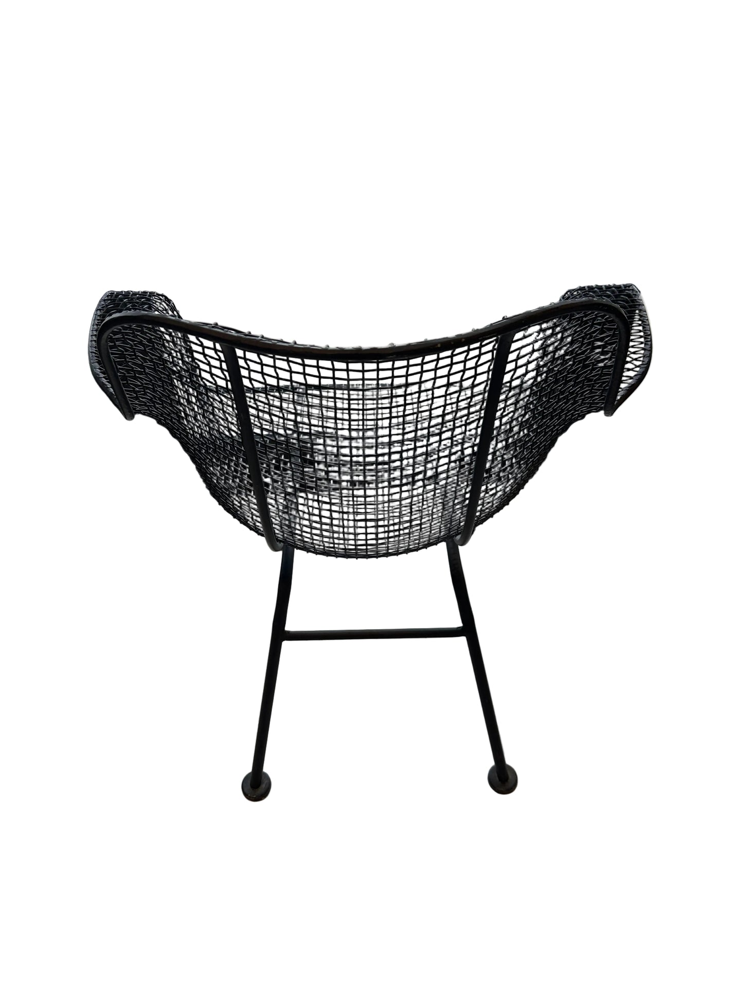 Rear view of black wire-mesh Russel Woodard chair on splayed iron legs