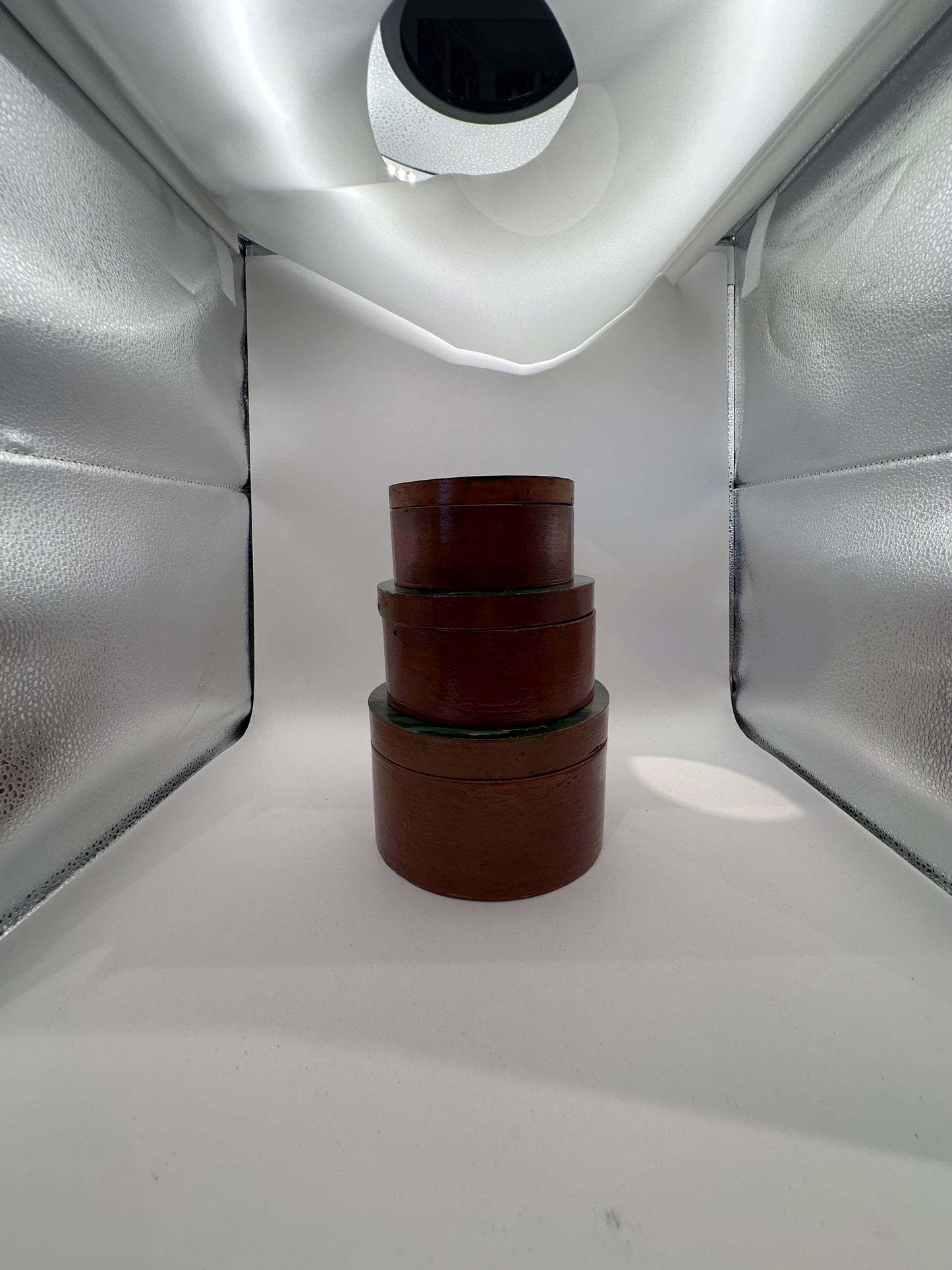 Nesting set of three reddish-brown round boxes with painted lids, front view