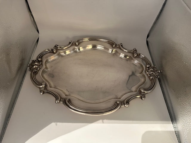 Vintage Rococo Revival silver plate oval tray with scrolled rim, angled view in light box