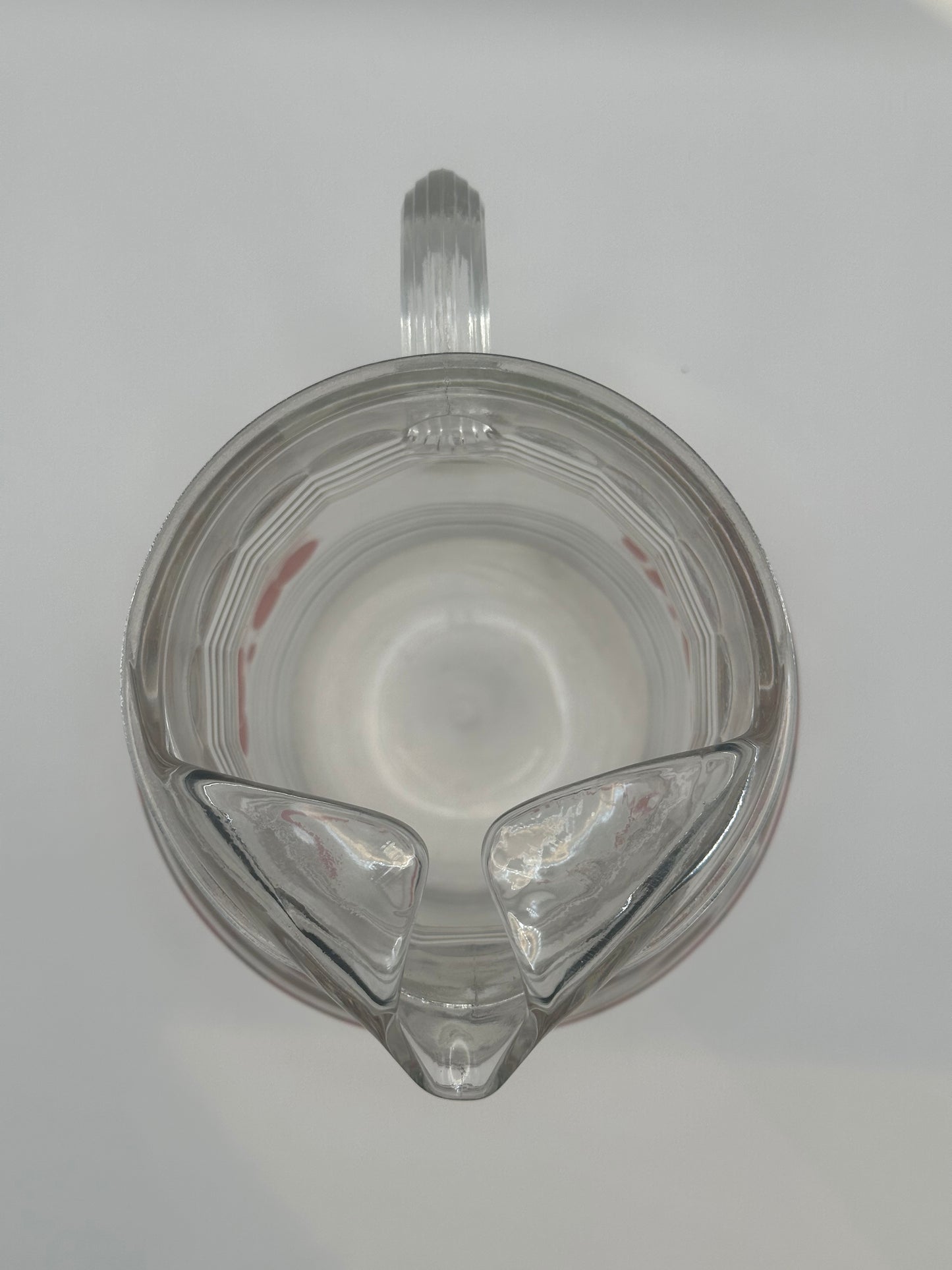 Top-down view into the glass pitcher showing its spout, handle and ribbed clear base