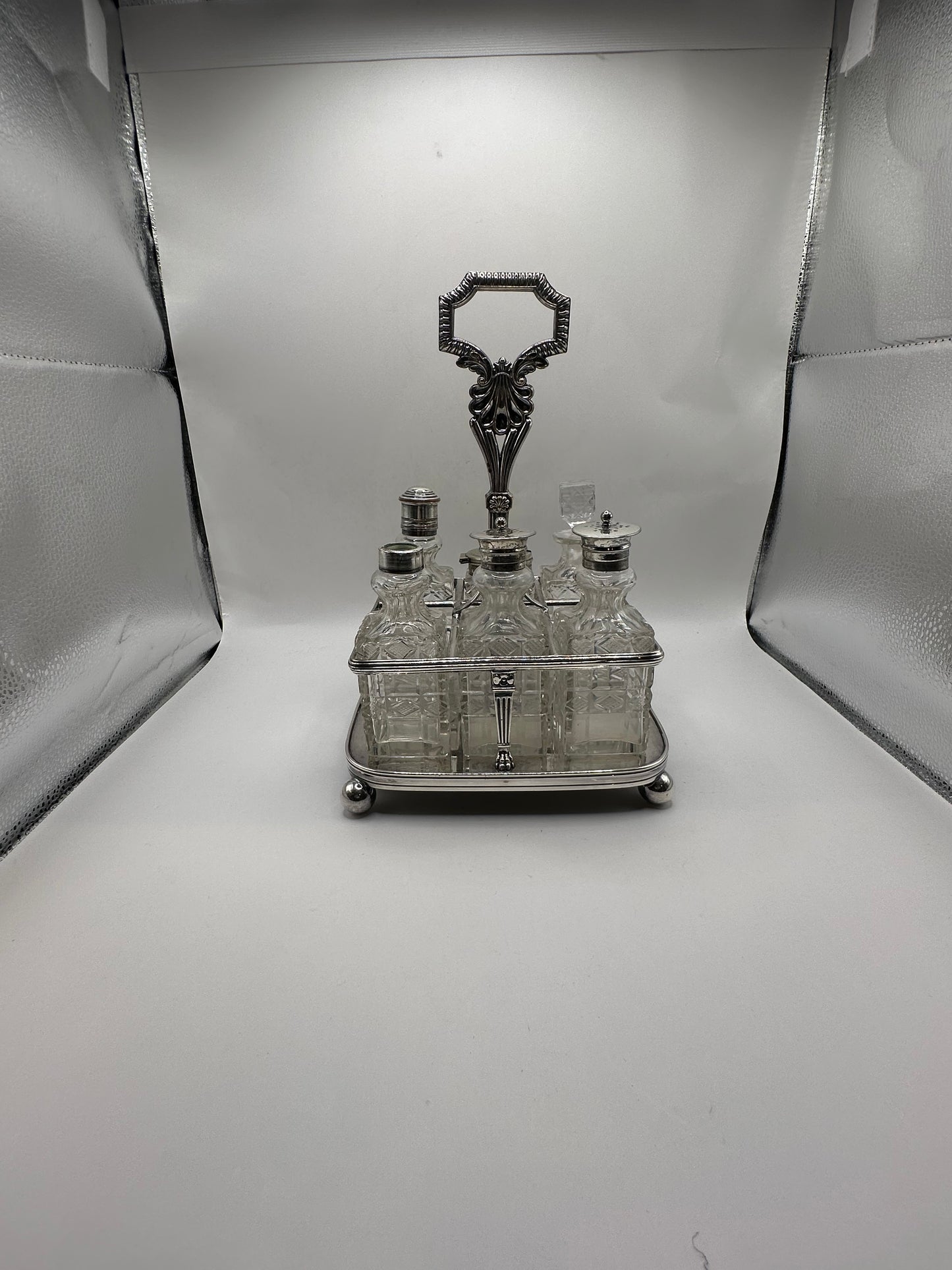 Antique cruet set fully assembled, all cut-glass bottles seated in the silver caddy, front view