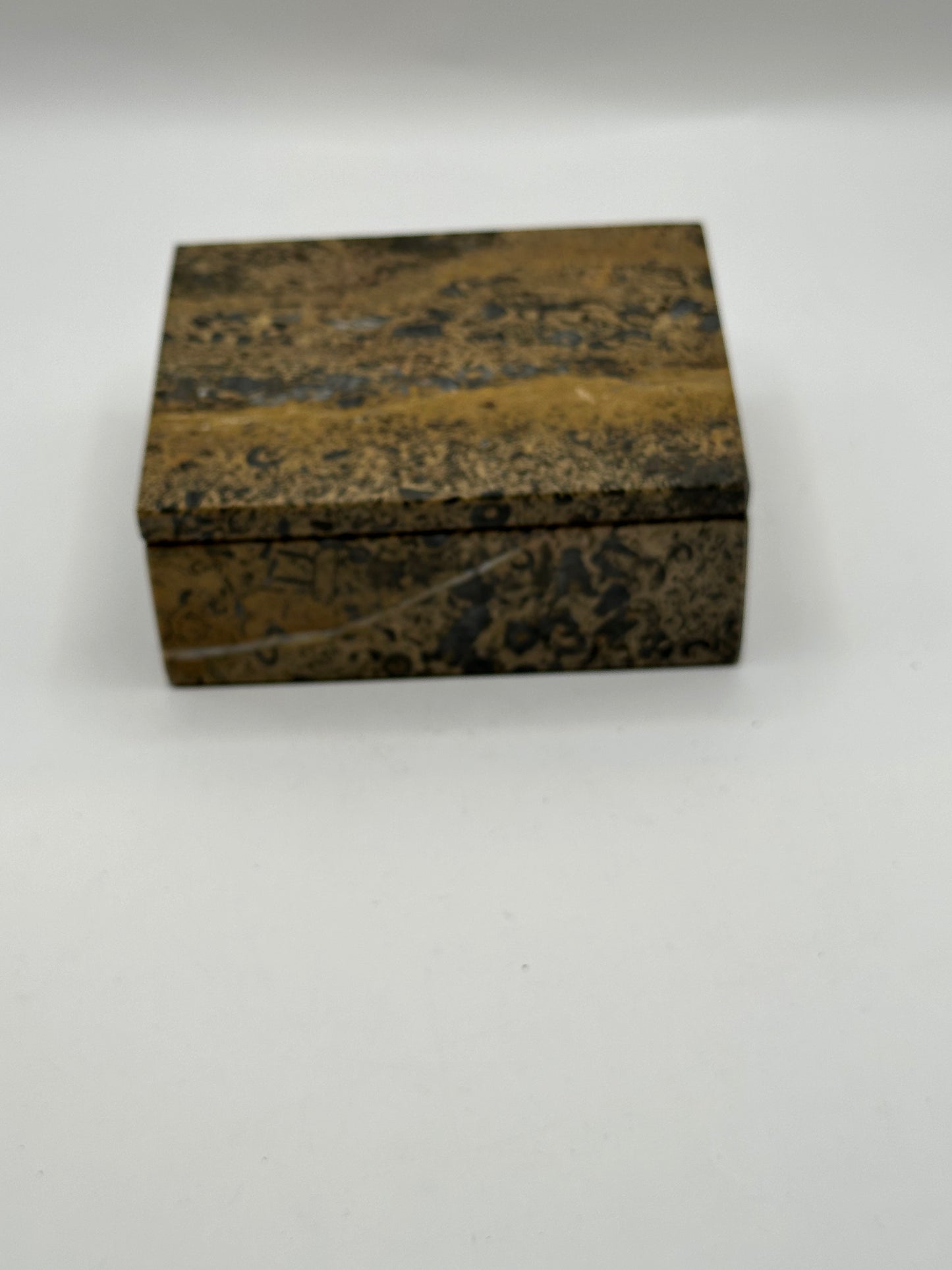Closed brown stone lidded box, angled view highlighting black and tan veining