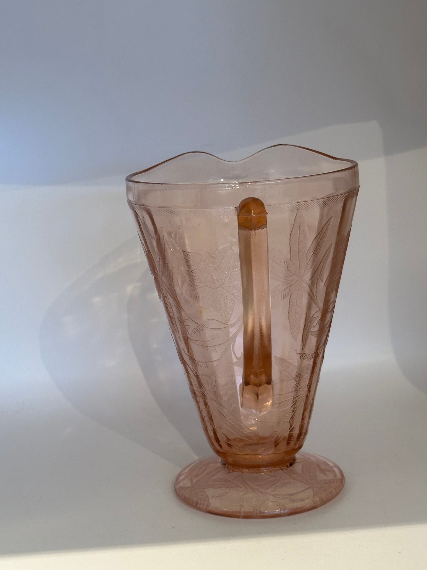 Pink Depression glass pitcher, back view showing handle and etched floral panels