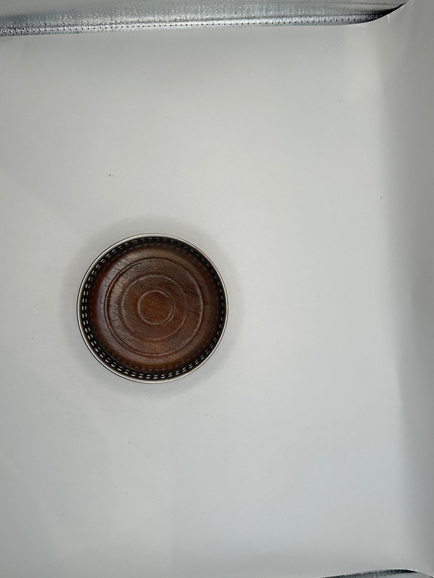 Overhead view of the bottle coaster's turned wood base within the beaded silver rim