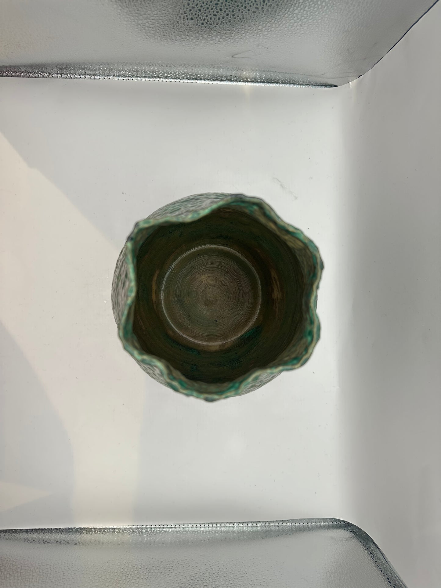 Top-down view into the tall stoneware vessel showing the wheel-thrown interior