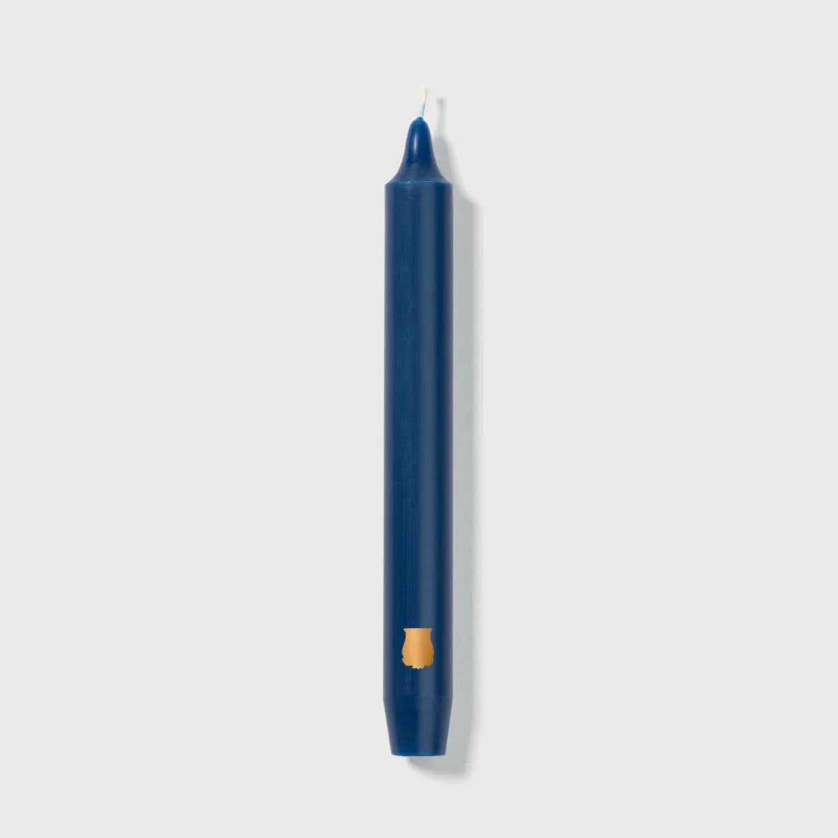 Navy blue Trudon Madeleine taper candle standing upright with a gold crest mark