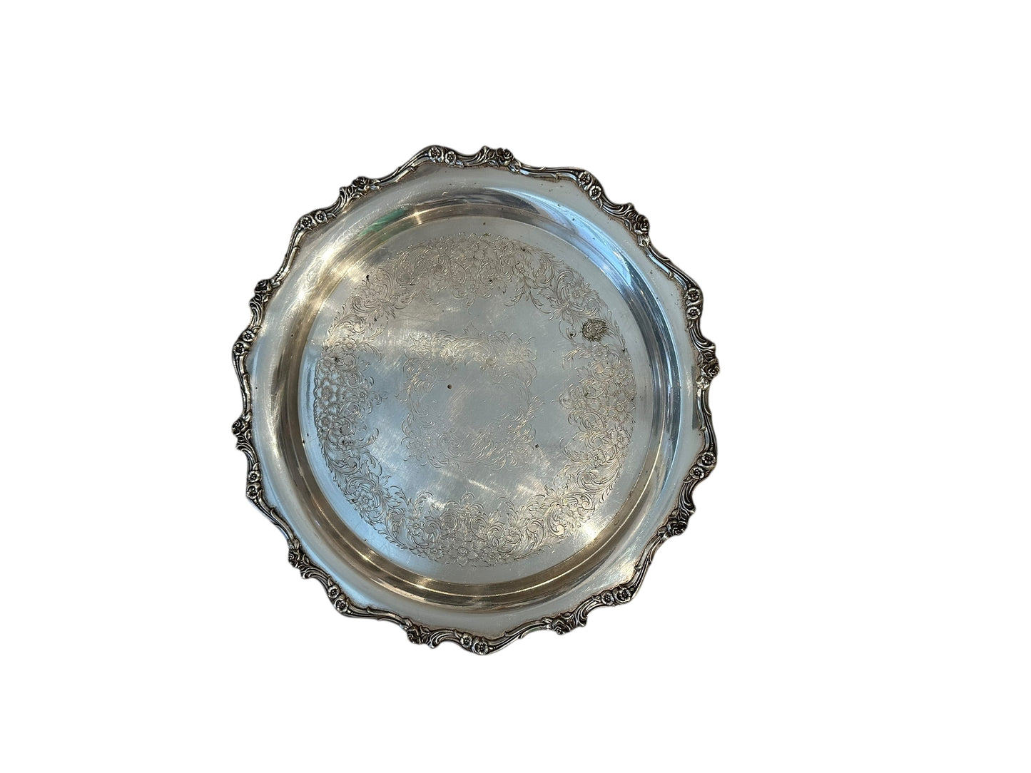 Vintage round silverplate serving tray, scalloped scroll border framing engraved floral center, top view
