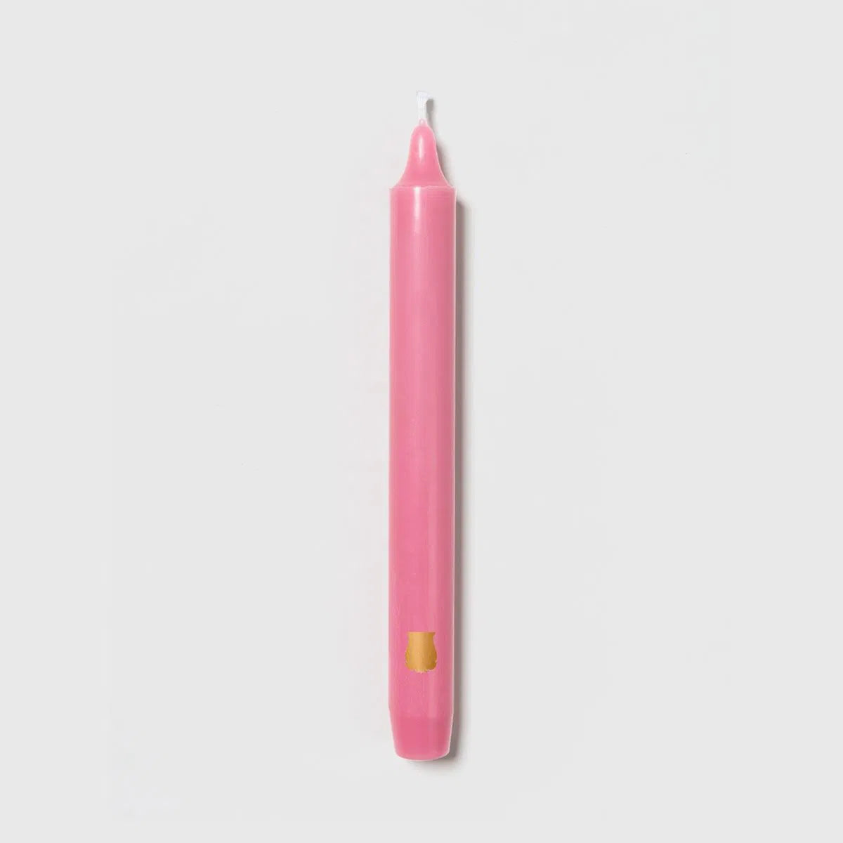 Rose pink Trudon Madeleine taper candle upright with an embossed gold crest