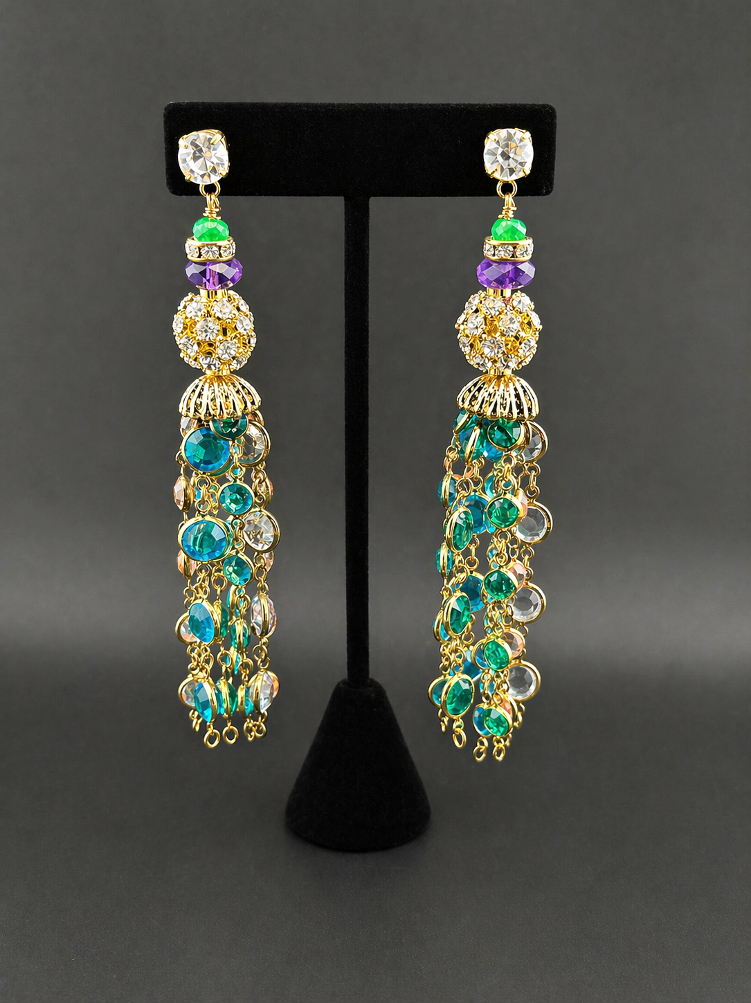 Chandelier gemstone tassel earrings with crystal ball and teal beaded fringe, on black stand