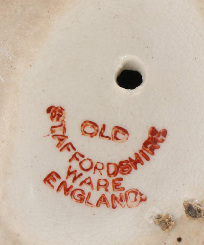 Underside of an antique Staffordshire dog showing the red 'Old Staffordshire Ware England' maker's mark.