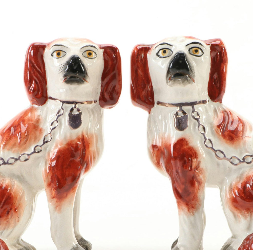 Close-up of the antique Staffordshire spaniels' faces, painted features with black noses and gold neck chains.