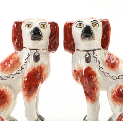 Close-up of the antique Staffordshire spaniels' faces, painted features with black noses and gold neck chains.