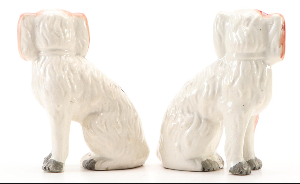 Rear view of the pair of antique Staffordshire spaniel figurines showing flat undecorated white backs.