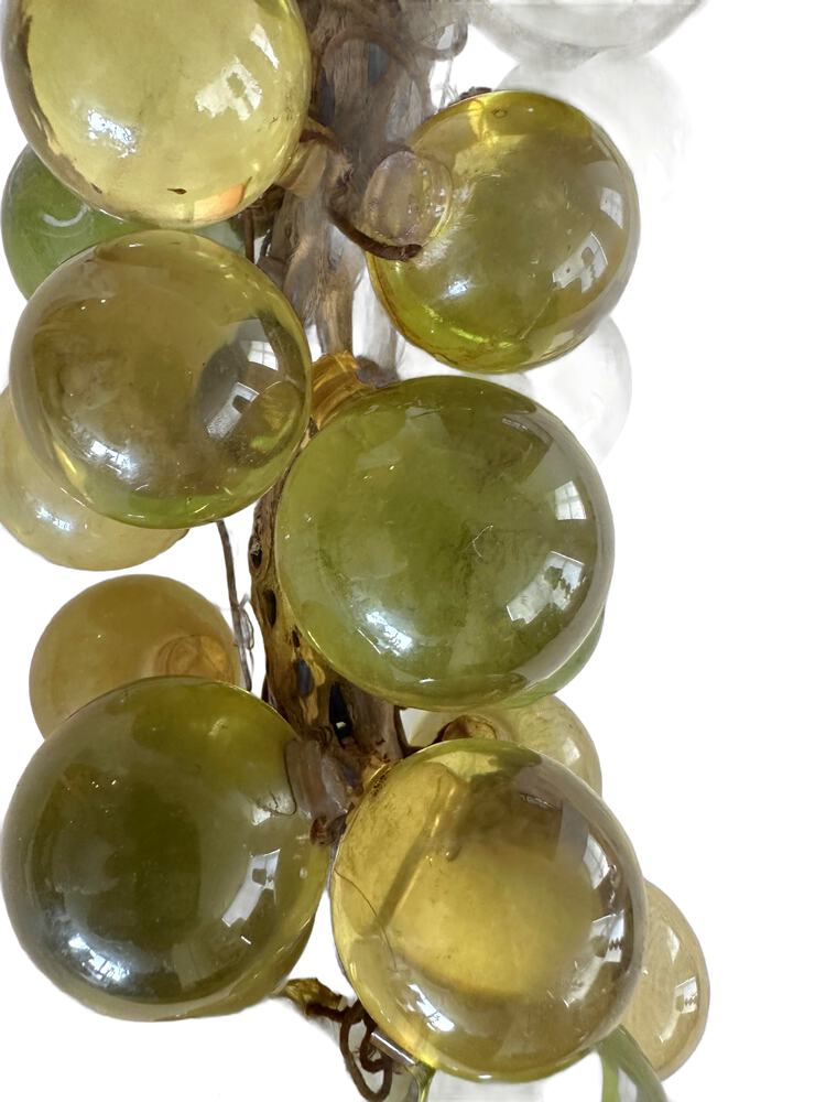 Close-up detail of the vintage acrylic grape cluster, glossy green and yellow translucent spheres wired together.