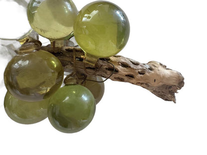 Angled close-up of vintage acrylic green grapes clustered on a gnarled natural wood stem.