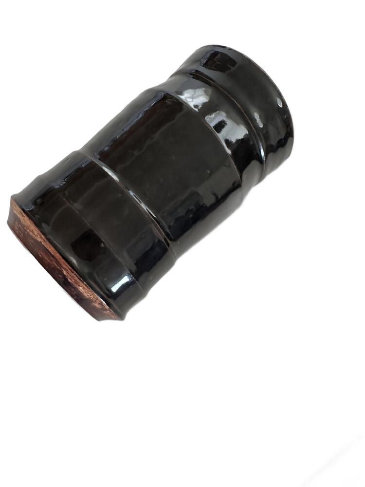 Studio pottery vase tilted on its side, glossy dark glaze with reddish clay base.