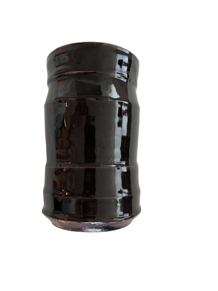 Studio pottery vase, front view of the ribbed cylinder with glossy near-black glaze.