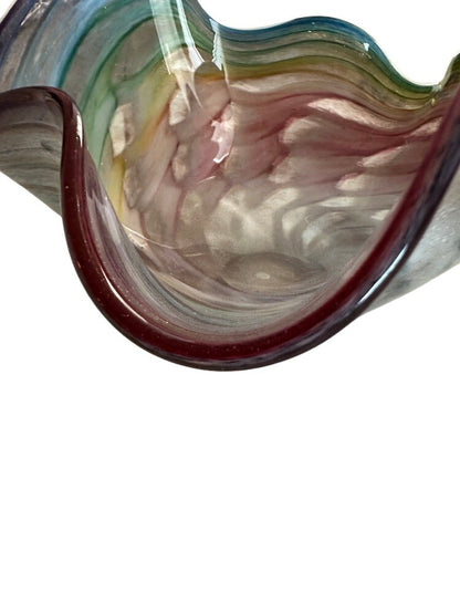 Close-up of the ruffled rim of the Murano style glass bowl, deep red edge over rainbow swirl