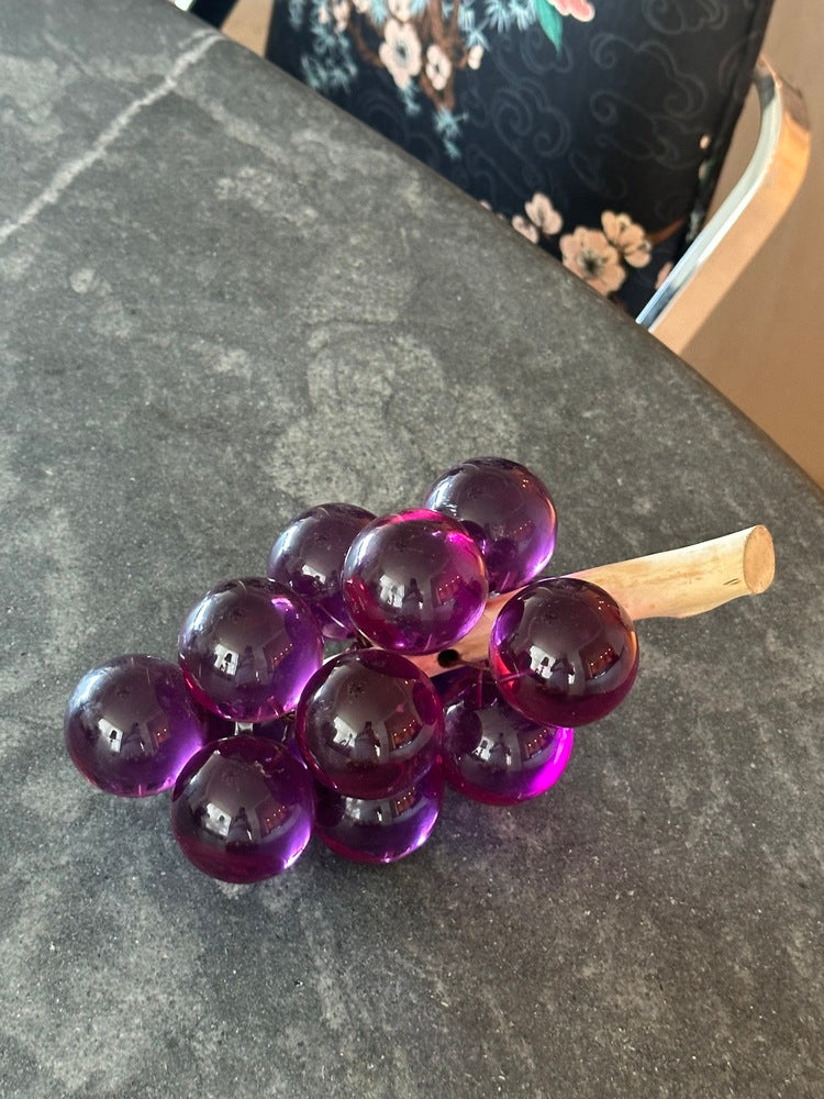 MCM purple acrylic grapes cluster on a driftwood stem resting on a gray stone countertop