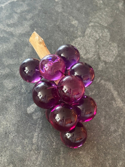 MCM purple acrylic grapes cluster on a driftwood stem, top view on gray stone