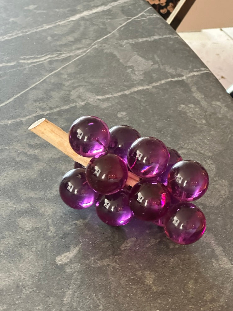 MCM purple acrylic grapes cluster on a driftwood stem, angled view on a gray countertop