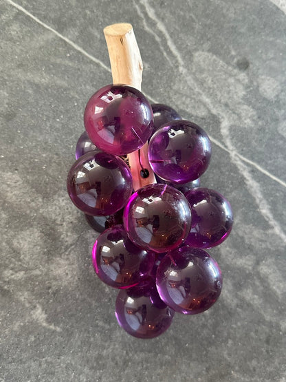 MCM purple acrylic grapes on a driftwood stem standing stem-up on gray stone