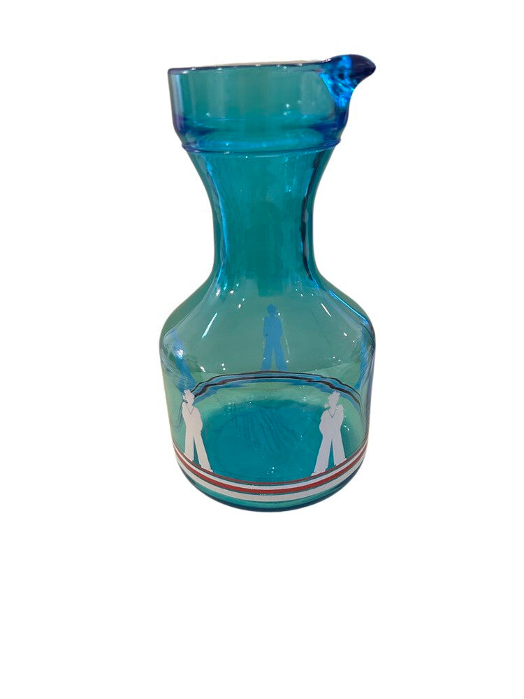 Blue glass sailor-motif carafe, side view showing pour spout, sailor figure and striped band.