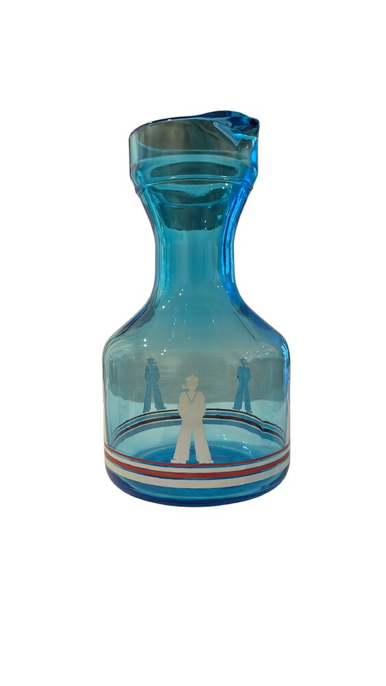 Blue glass sailor-motif decanter shown alone, with white sailor figure and striped band; small chip on the rim.