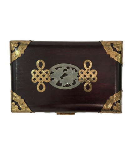 Top of the Asian wood box with carved jade medallion and brass endless-knot motifs