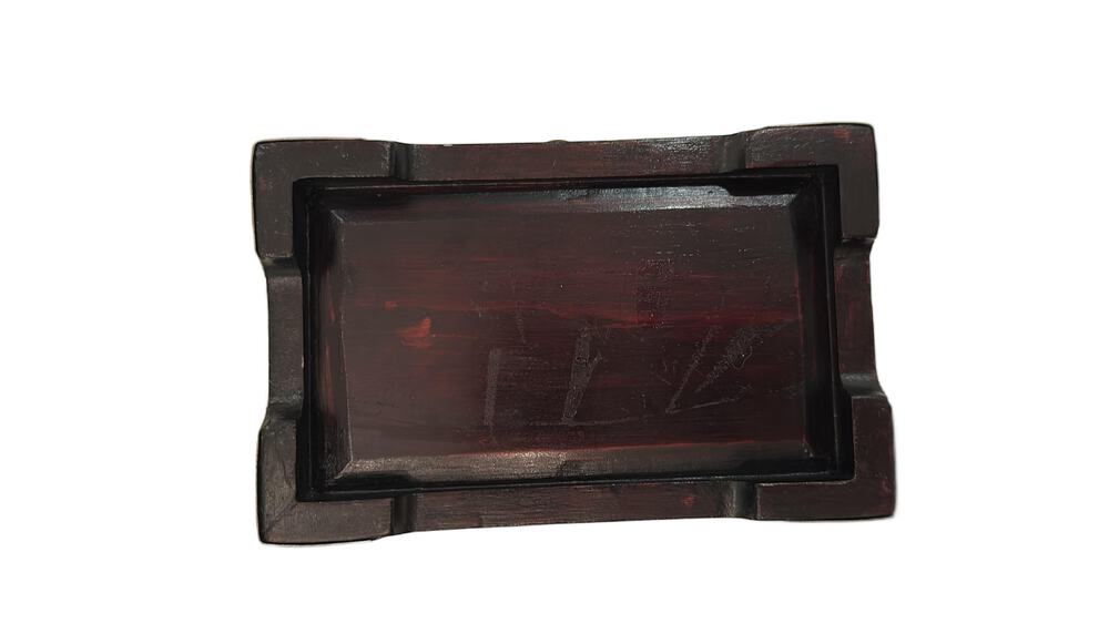Underside of the box showing dark reddish wood grain and faint markings