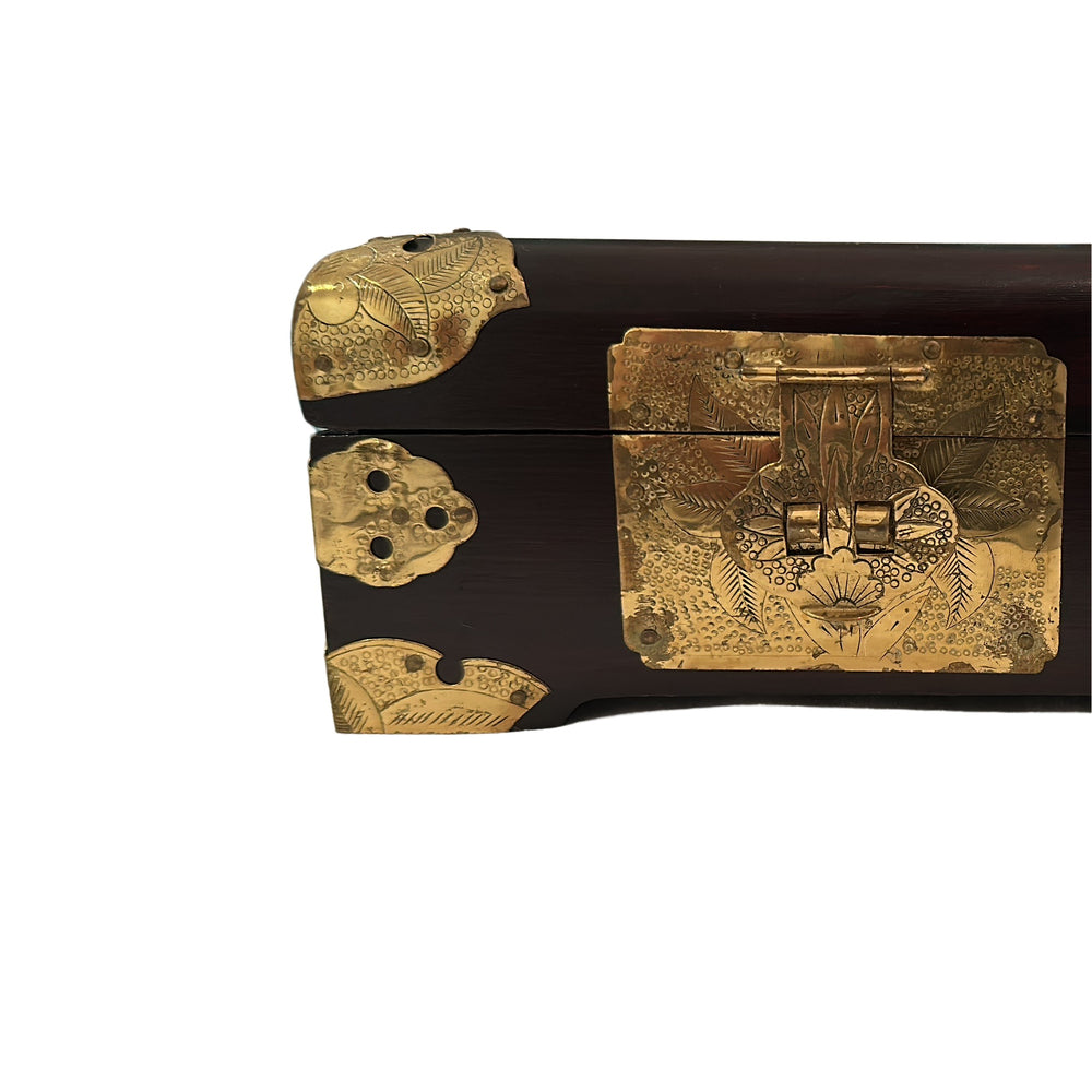 Close-up of the engraved brass front clasp, latch, and corner mount on the box