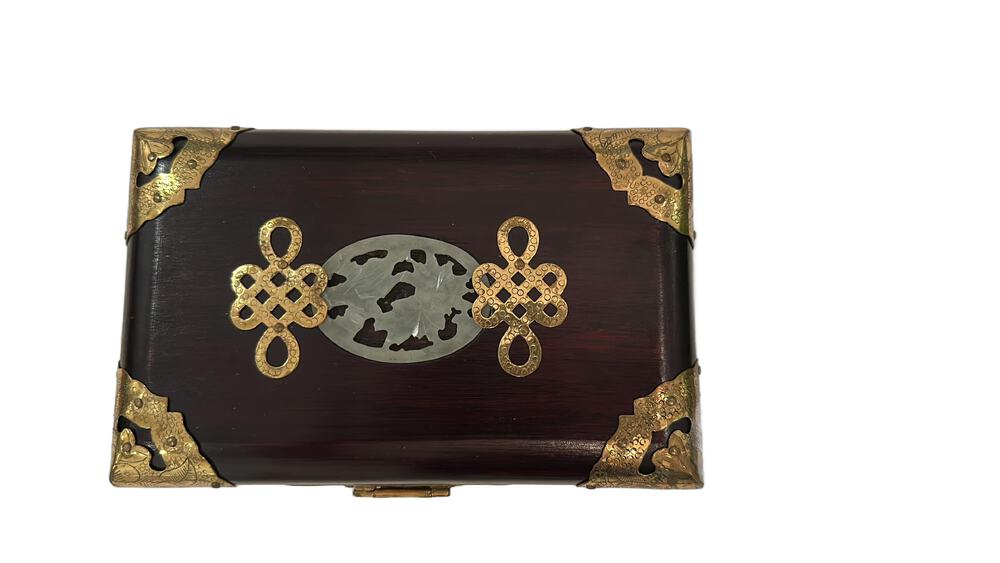 Angled top view of the wood box's carved jade medallion and brass corner mounts