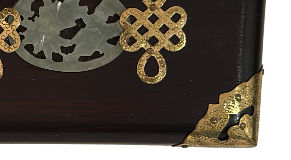 Close-up of the carved jade medallion and brass endless-knot on the box lid