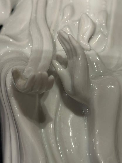 Close-up of a blanc de Chine porcelain figure's delicately sculpted hands on the table lamp