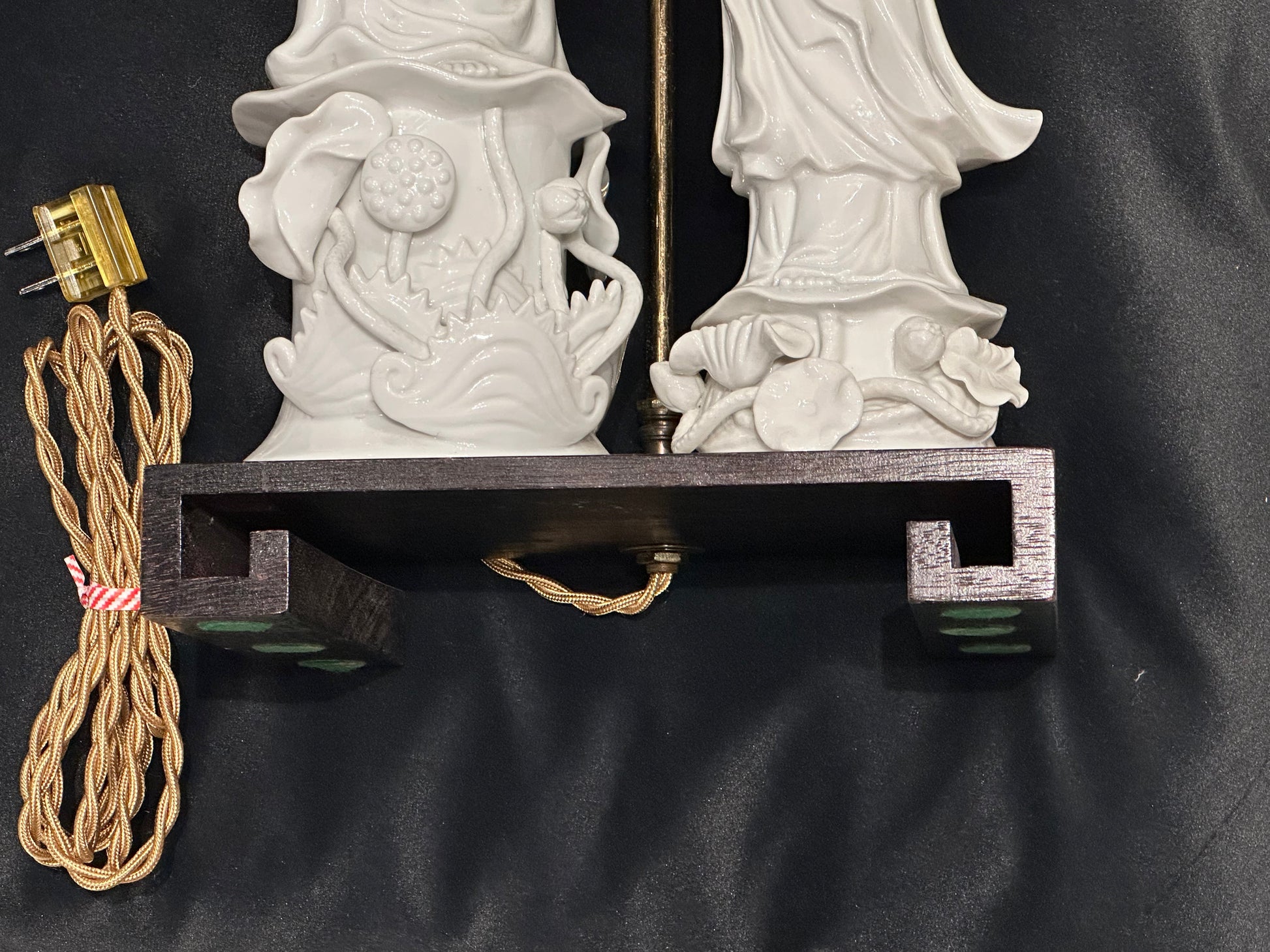 Underside of the lamp's dark wood Greek-key base with newly rewired gold cloth cord and plug