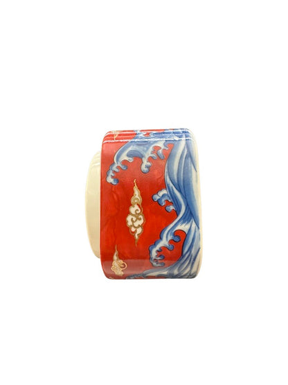 Vintage porcelain small box, side view with blue cresting waves and gold clouds on red ground.