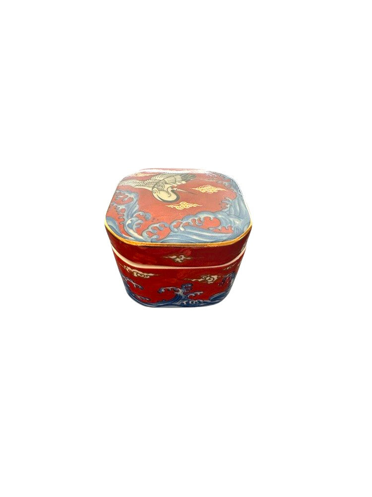 Vintage porcelain small box, assembled, showing red crane lid and blue wave base, three-quarter view.