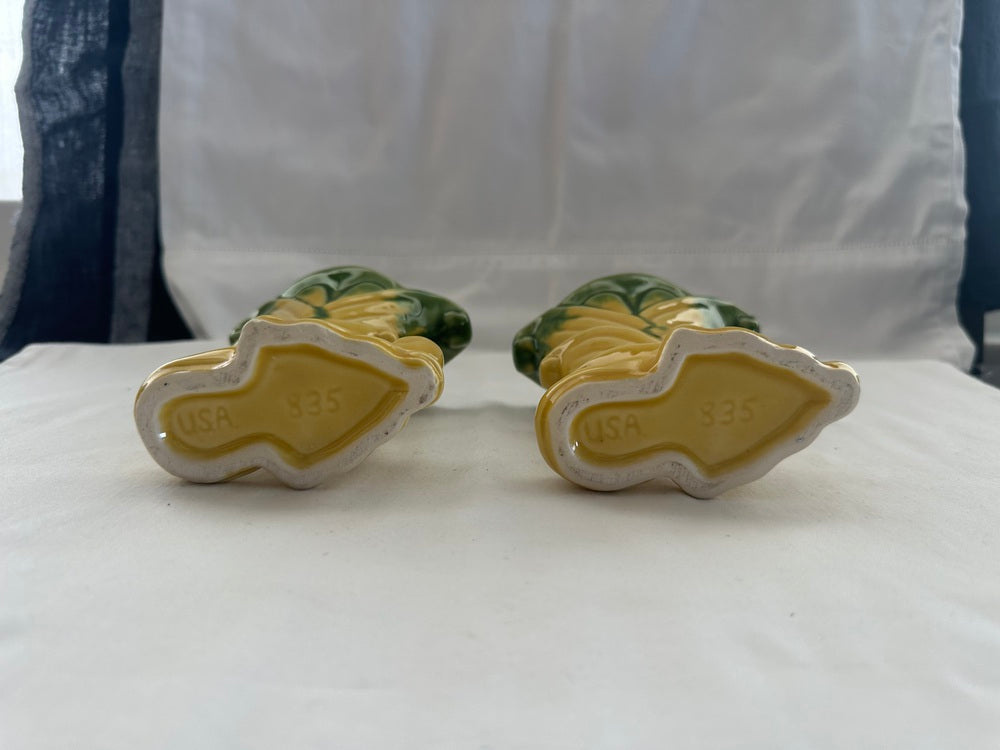 Vintage Shawnee Pottery vases tipped to reveal unglazed bases marked 'USA 535' against white cloth