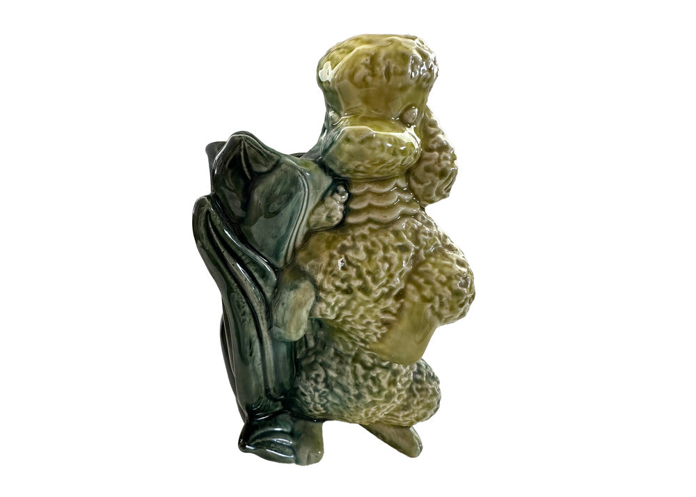 Vintage Hull poodle vase, yellow-green glazed seated poodle against dark green leaf-form vessel, three-quarter view