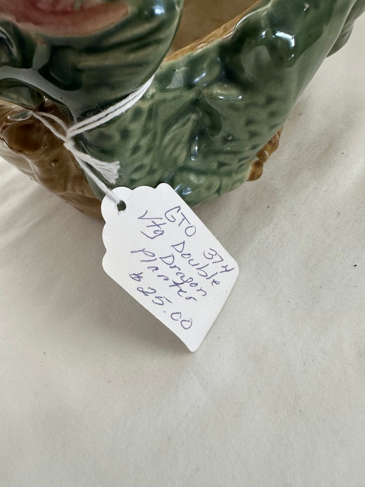 Close-up of the planter's handwritten paper hang tag beside the green glazed dragon body