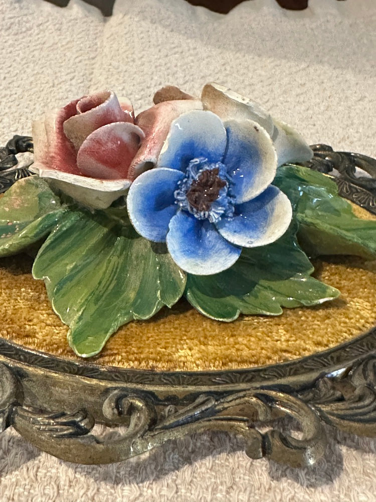 Close-up of blue porcelain anemone and pink rose with green leaves on gold velvet plaque