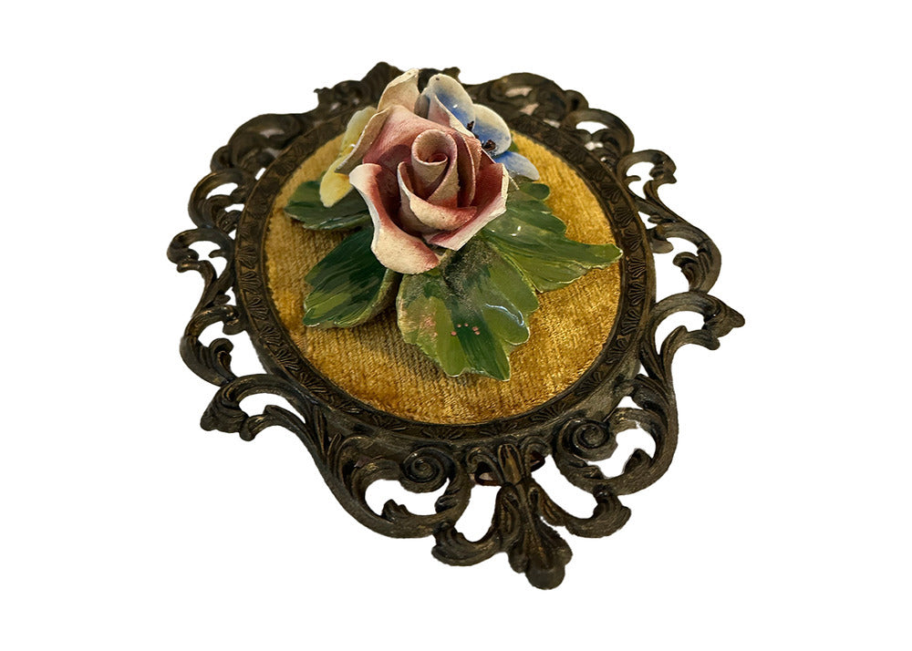 Top angled view of porcelain pink rose and blue blossom on gold velvet plaque in scrolled metal frame