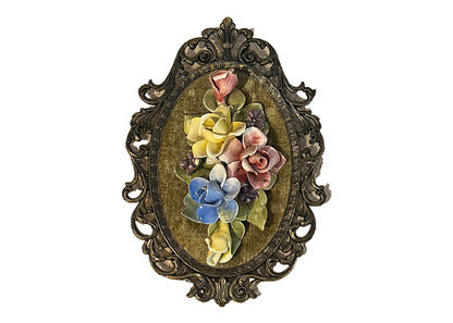 Angled front view of Capodimonte porcelain floral plaque, pink, yellow and blue roses on green velvet in scrolled gilt frame